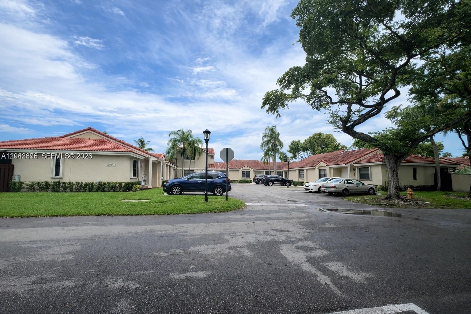 A parking lot sits in front of single-story residential buildings with red tile roofs — 6012 NW 172nd Terr Cir, Hialeah FL 33015, HIALEAH, FL