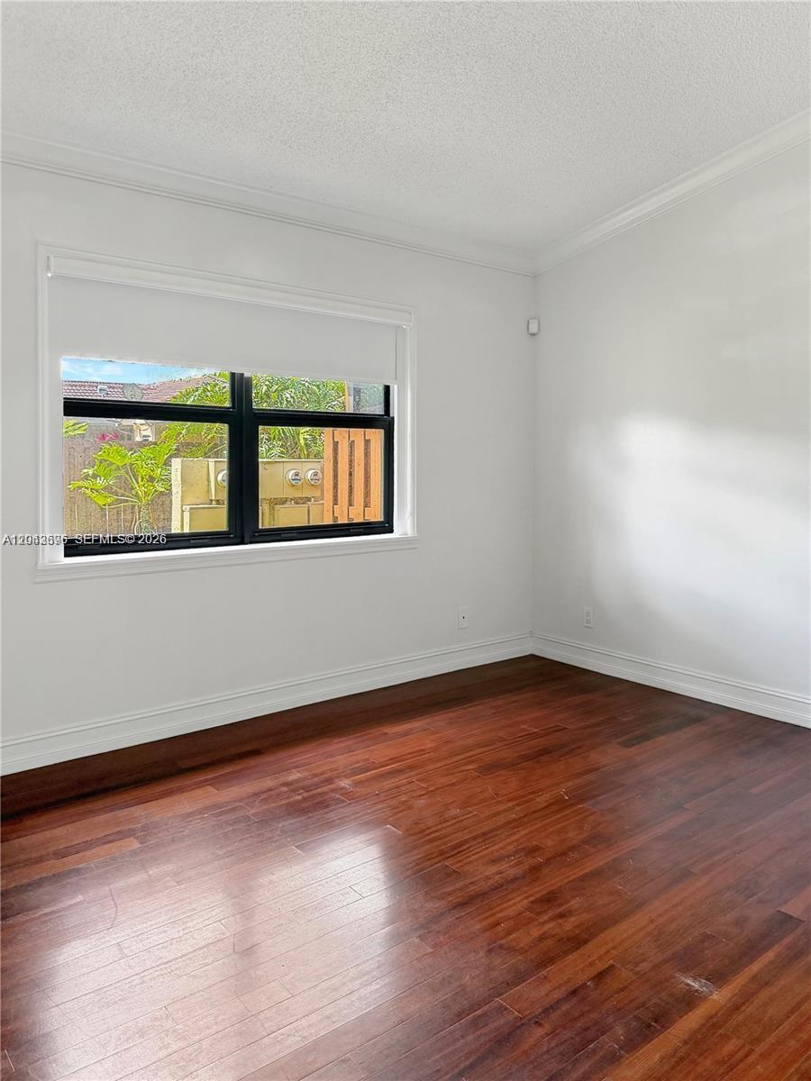 An empty room features white walls, dark wood flooring, and a window with a blind — 6012 NW 172nd Terr Cir, Hialeah FL 33015, HIALEAH, FL