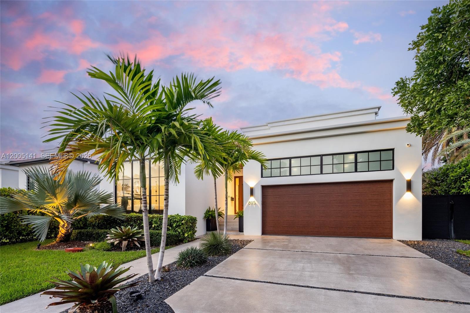 A modern white house with a wood garage door, palm trees, and a concrete driveway — 895 NE 76th St, Miami FL 33138, MIAMI, FL