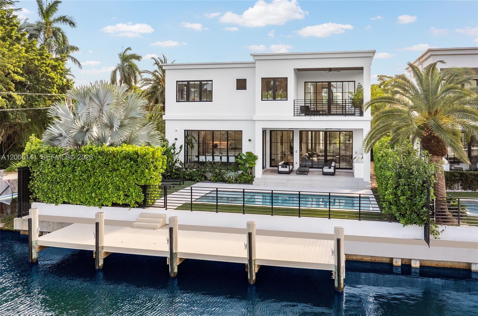 A modern two-story white house features a swimming pool, a private dock, and lush landscaping — 895 NE 76th St, Miami FL 33138, MIAMI, FL