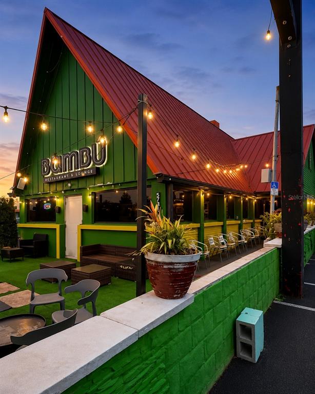 An exterior view of a green restaurant with a red metal roof and patio seating — 5731 S. ORANGE BLOSSOM TRAIL, ORLANDO, FL