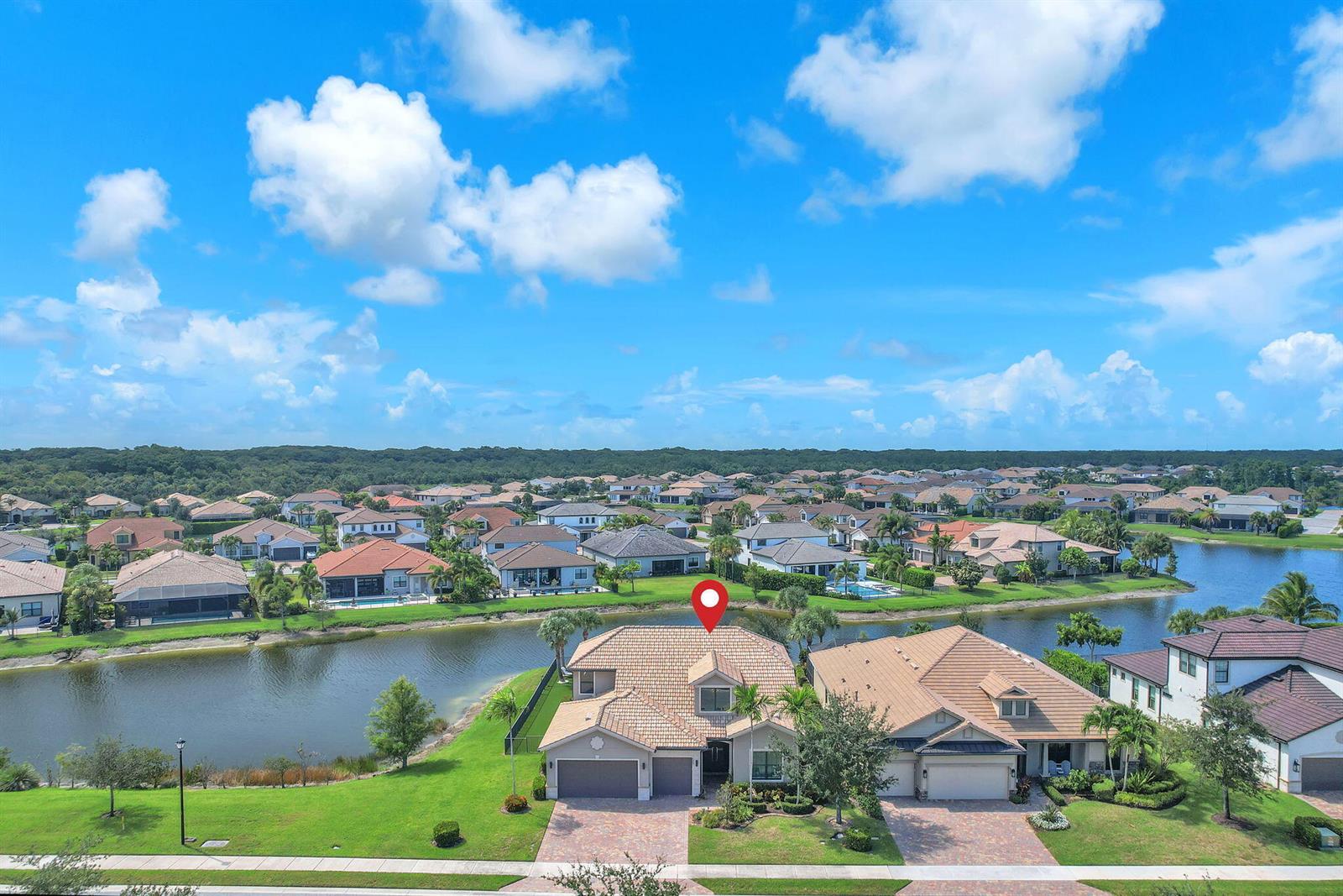 An aerial view shows a two-story house with a tiled roof next to a lake — 507 Sonoma Isles Circle, Jupiter FL 33478, JUPITER, FL