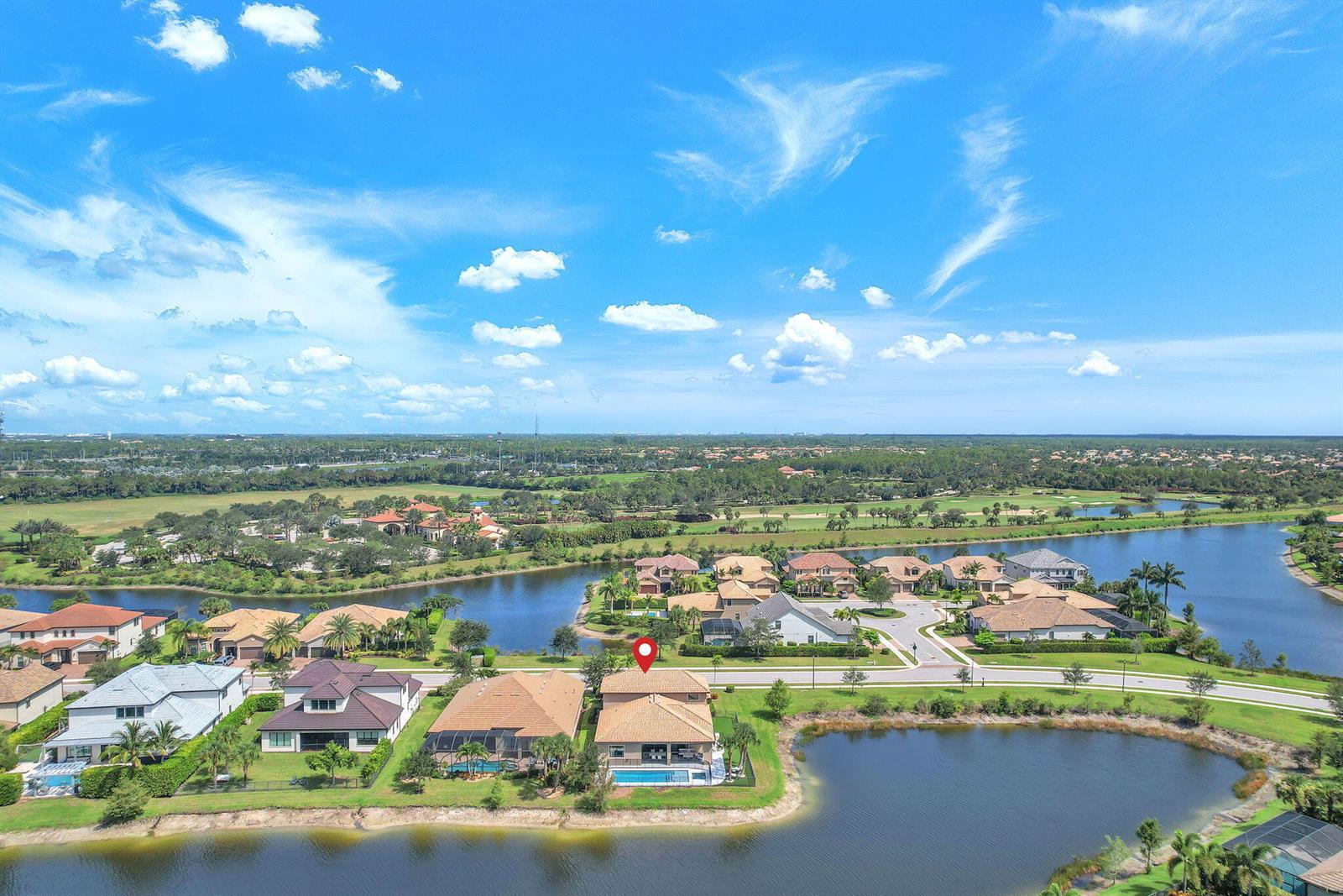 An aerial view shows a residential neighborhood with houses situated along a lake — 507 Sonoma Isles Circle, Jupiter FL 33478, JUPITER, FL