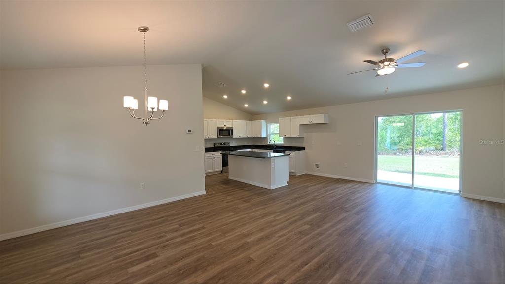 An open-concept kitchen and living area with wood-look flooring, white cabinetry, and a sliding door — 1353 W CARY DRIVE, CITRUS SPRINGS, FL