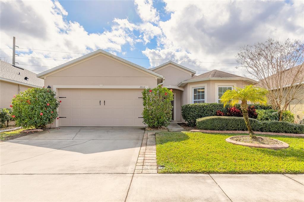 A single-story house with a beige stucco exterior, a two-car garage, and a front lawn — 2612 STAR CORAL LANE, NEW SMYRNA BEACH, FL