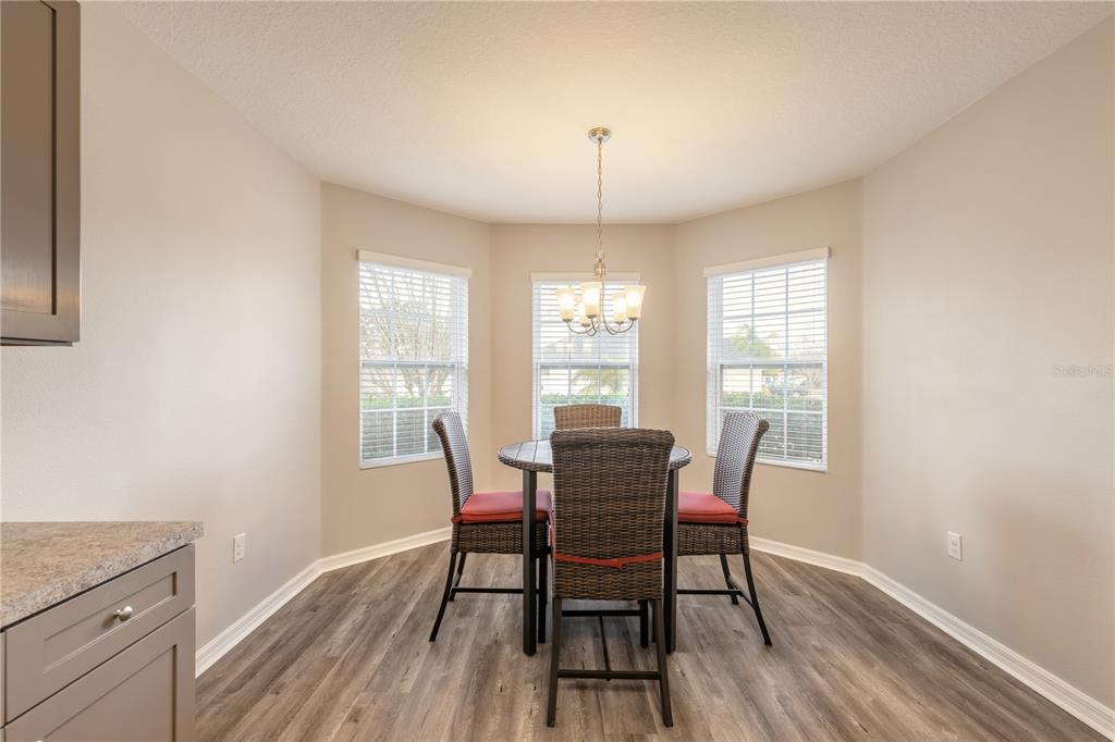 A dining nook features a round table with four wicker chairs under a pendant light — 2612 STAR CORAL LANE, NEW SMYRNA BEACH, FL