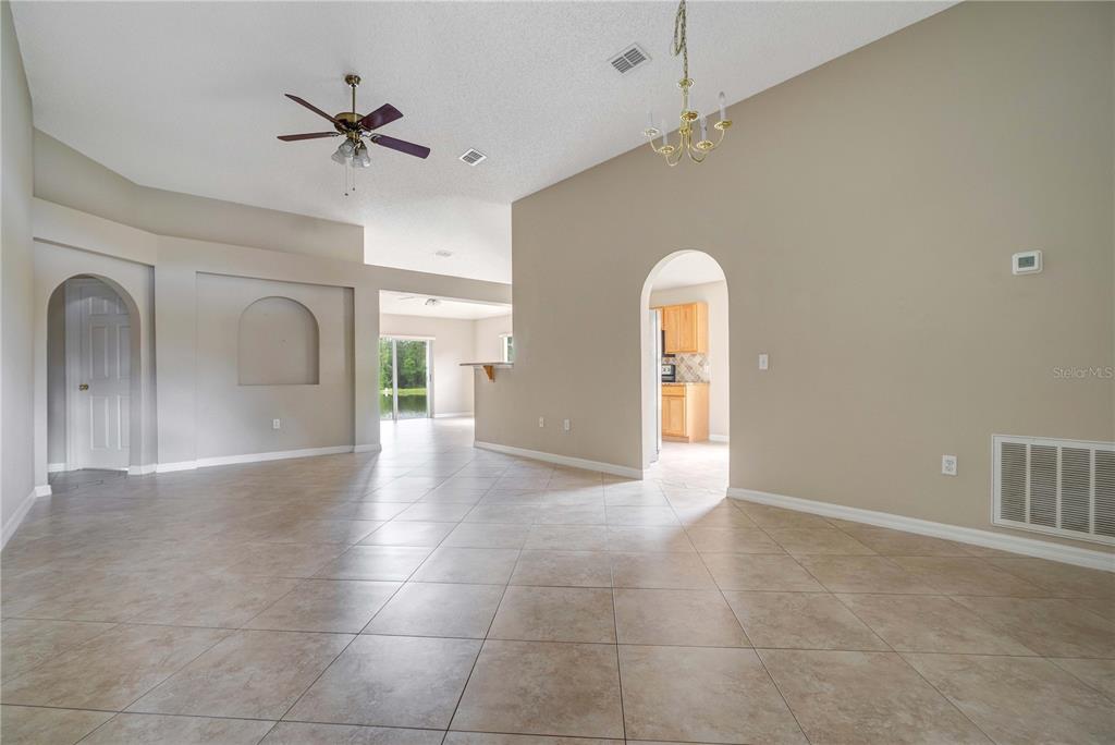 An open-concept living area features tile flooring, arched doorways, a ceiling fan, and a chandelier — 1845 CORNER MEADOW CIRCLE, ORLANDO, FL