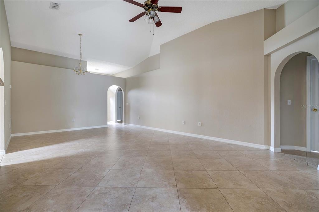 A spacious living area features vaulted ceilings, tile flooring, and an arched entryway — 1845 CORNER MEADOW CIRCLE, ORLANDO, FL