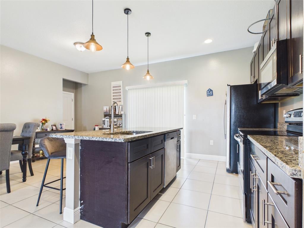 A kitchen features dark wood cabinets, granite countertops, a center island, and tile flooring — 14942 SW 24TH CIRCLE, OCALA, FL