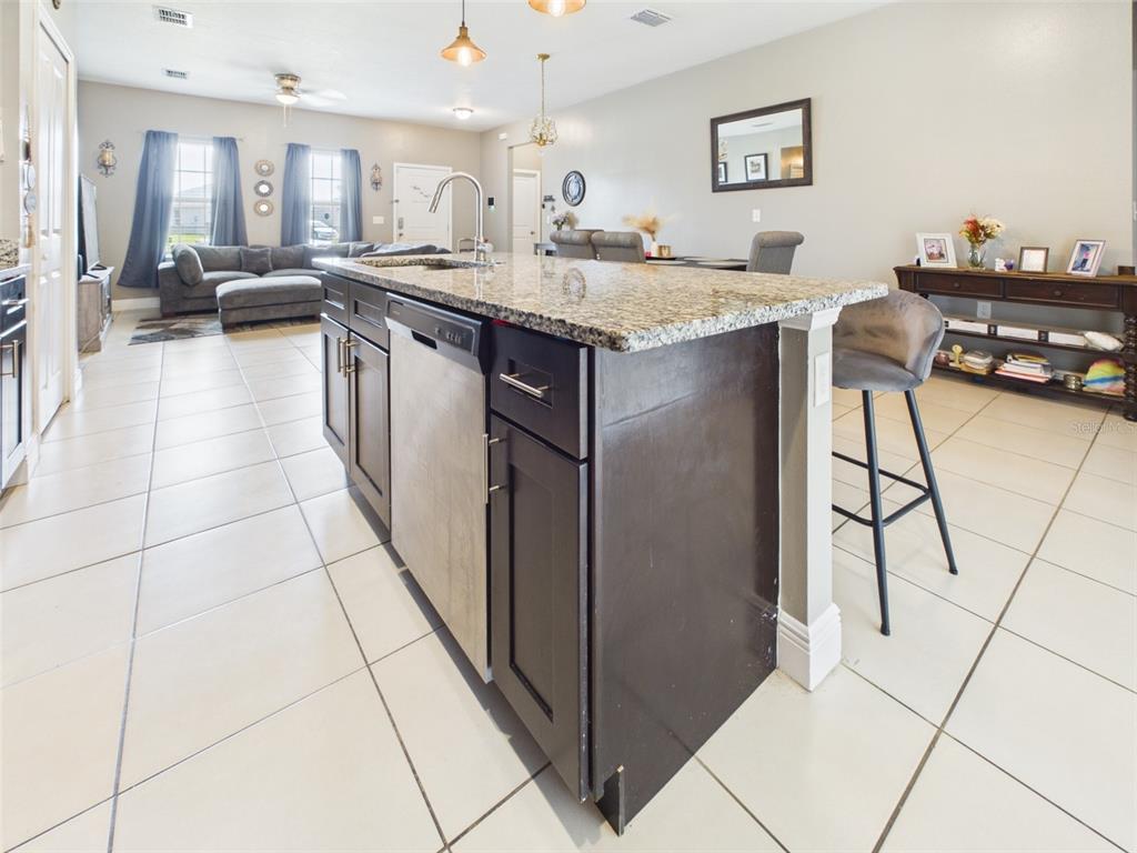 A kitchen island with dark cabinets and granite countertops sits in an open-concept living space — 14942 SW 24TH CIRCLE, OCALA, FL