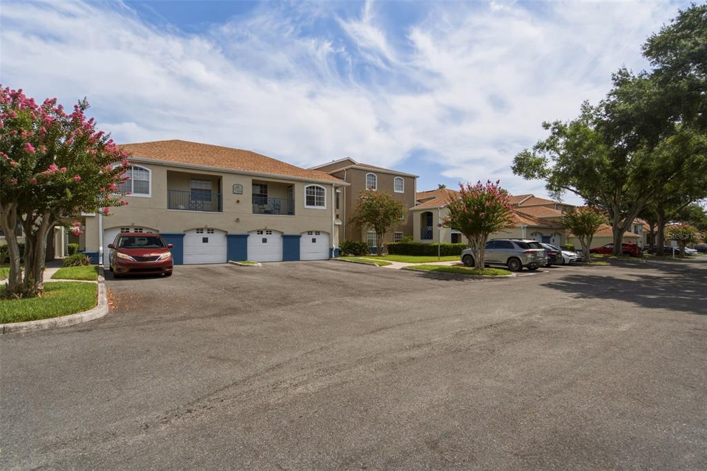 An exterior view of a multi-story apartment building with attached garages and a parking lot — 7300 WESTPOINTE BOULEVARD UNIT 725, ORLANDO, FL
