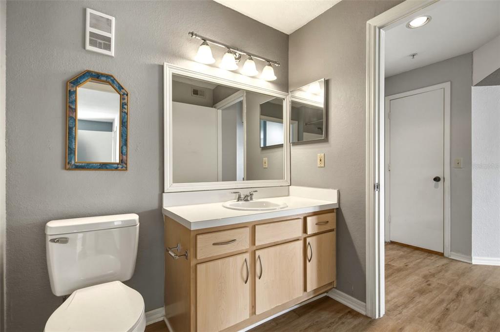 A bathroom features a light wood vanity, a white countertop, and a gray-painted wall — 7300 WESTPOINTE BOULEVARD UNIT 725, ORLANDO, FL