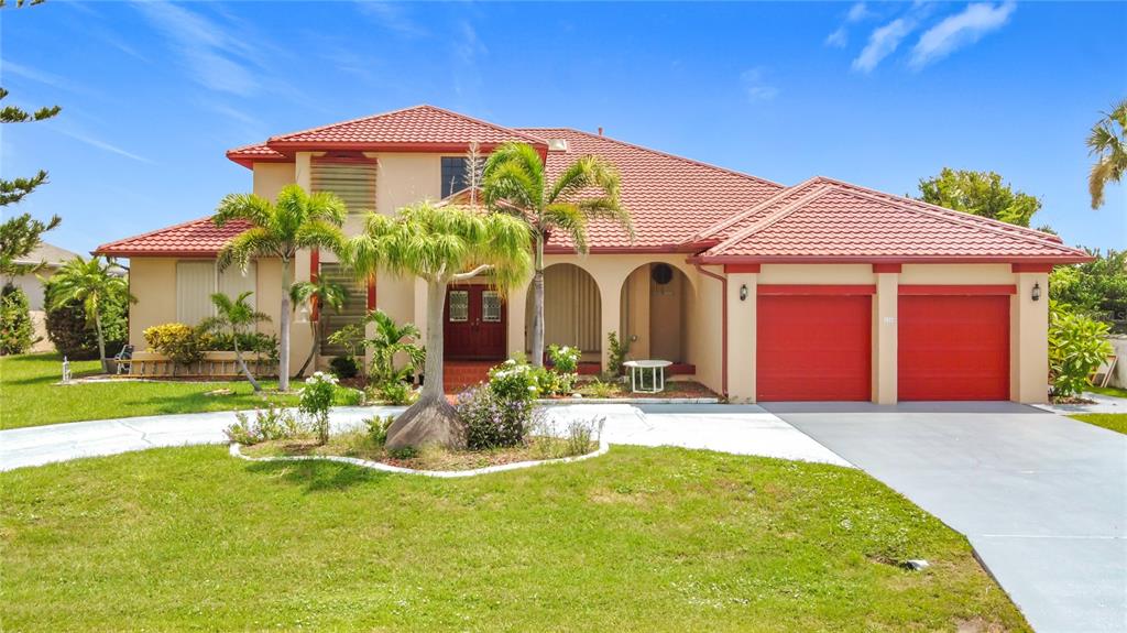 A two-story house with a red tile roof, red garage doors, and a front lawn — 134 SEVILLE PLACE SW, PORT CHARLOTTE, FL