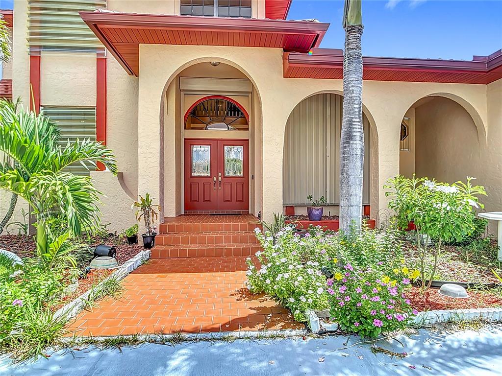 The exterior entrance features a red double door, arched entryway, and brick-paved steps — 134 SEVILLE PLACE SW, PORT CHARLOTTE, FL