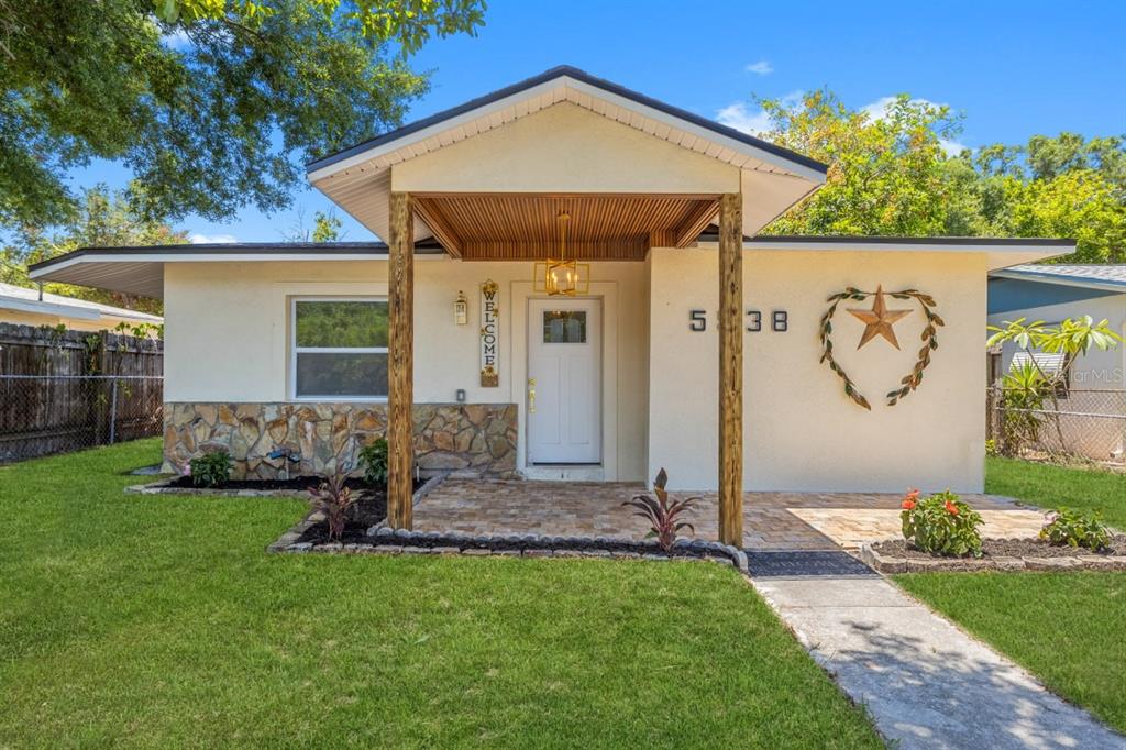 A single-story house with a stone-accented facade, a covered porch, and a wooden star decoration — 5538 6TH AVENUE N, ST PETERSBURG, FL
