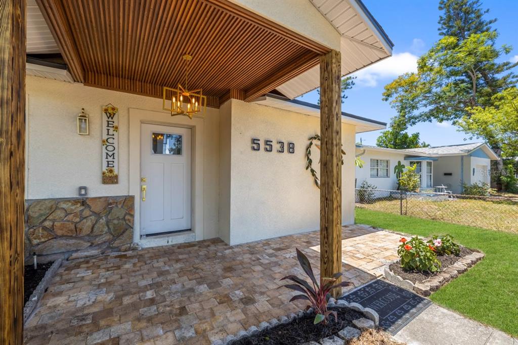 A front porch with stone pavers, a wooden ceiling, and a white front door — 5538 6TH AVENUE N, ST PETERSBURG, FL