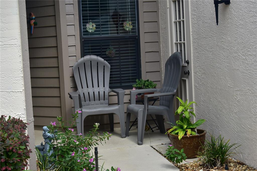 Two gray Adirondack chairs sit on a concrete patio in front of a window — 2243 WYNDAM DRIVE, SPRING HILL, FL
