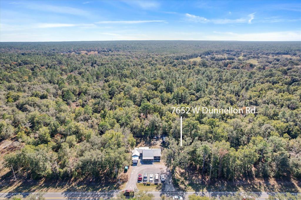 An aerial view shows a house surrounded by dense forest next to a paved road — 7652 W DUNNELLON ROAD, DUNNELLON, FL