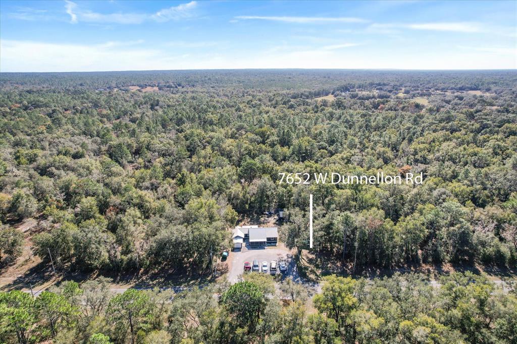 An aerial view shows a house surrounded by dense forest with a paved parking area — 7652 W DUNNELLON ROAD, DUNNELLON, FL