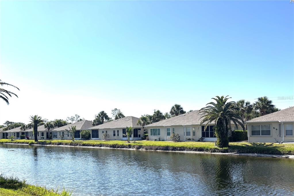 A row of single-story houses with palm trees sits along the edge of a canal — 1759 FOUNTAIN VIEW CIRCLE UNIT 1759, VENICE, FL
