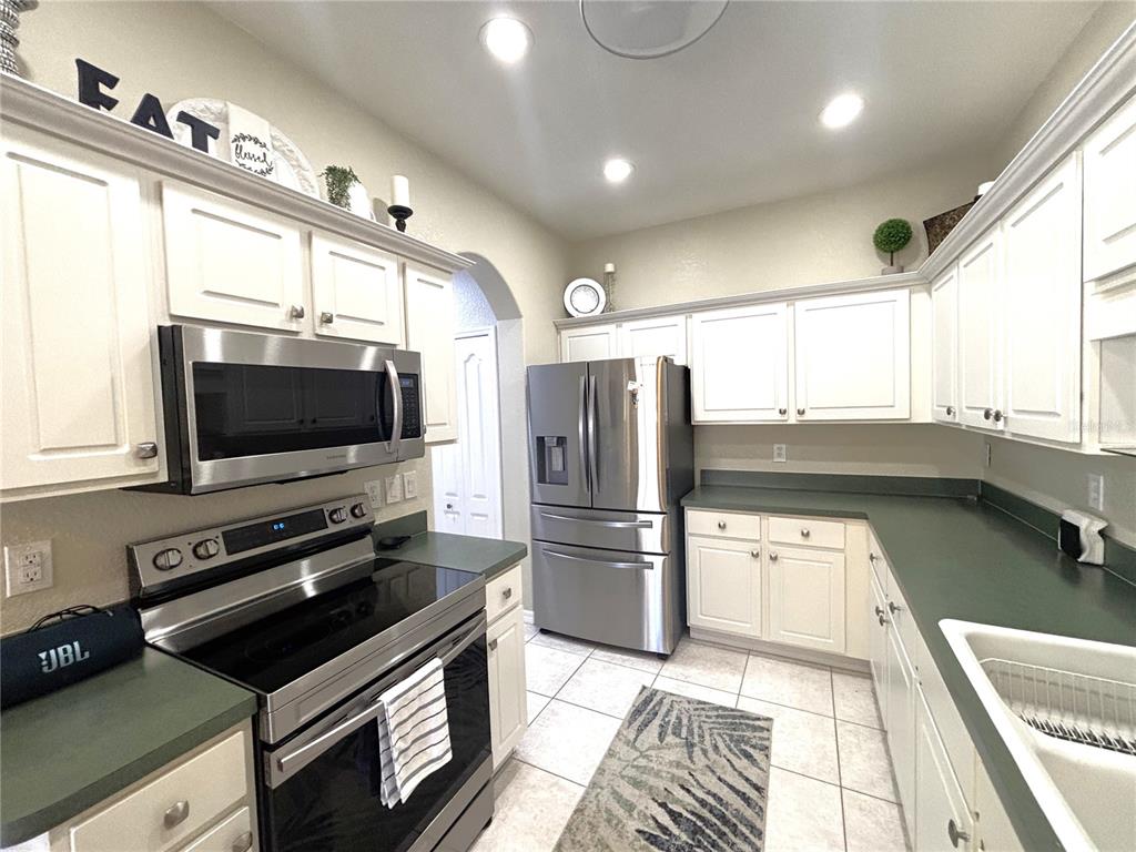 A kitchen features white cabinets, green countertops, stainless steel appliances, and tile flooring — 1759 FOUNTAIN VIEW CIRCLE UNIT 1759, VENICE, FL