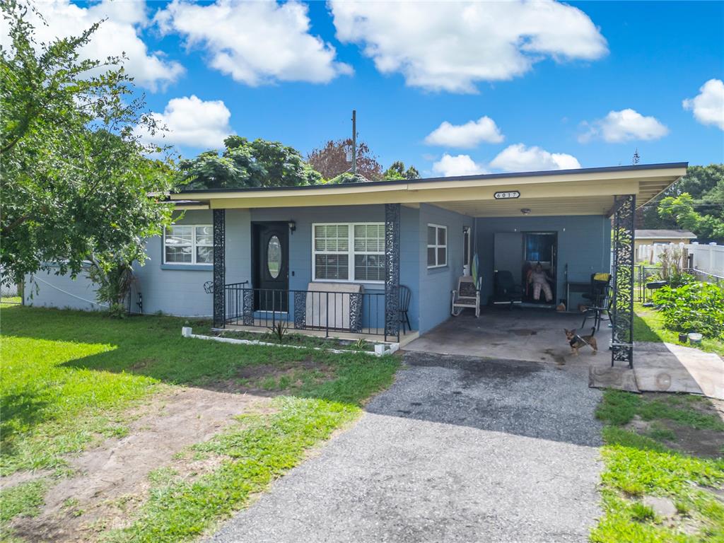A single-story house with a driveway and a tree under a vibrant sunset sky — 6017 CANDLEWOOD LANE, ORLANDO, FL