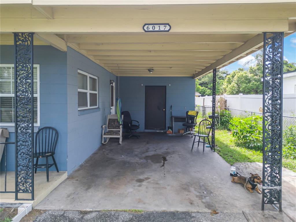 A blue house exterior features a covered concrete carport with decorative metal support columns — 6017 CANDLEWOOD LANE, ORLANDO, FL