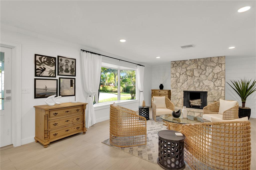 A living room features a stone fireplace, light wood flooring, and four woven armchairs — 1945 ANGLERS COVE, VERO BEACH, FL