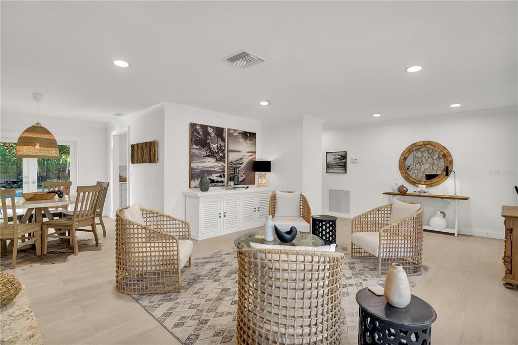 A bright living and dining area features light wood flooring, wicker chairs, and white walls — 1945 ANGLERS COVE, VERO BEACH, FL