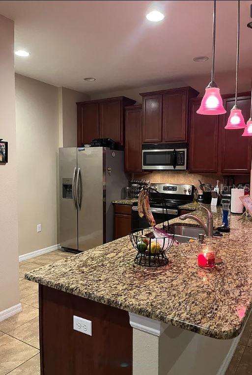 A kitchen features granite countertops, dark wood cabinetry, stainless steel appliances, and pendant lighting — 13805 RIVER FISH COURT, TAMPA, FL