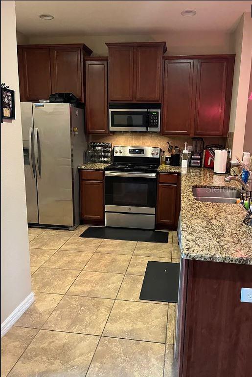 A kitchen features dark wood cabinets, stainless steel appliances, and granite countertops over tiled floors — 13805 RIVER FISH COURT, TAMPA, FL