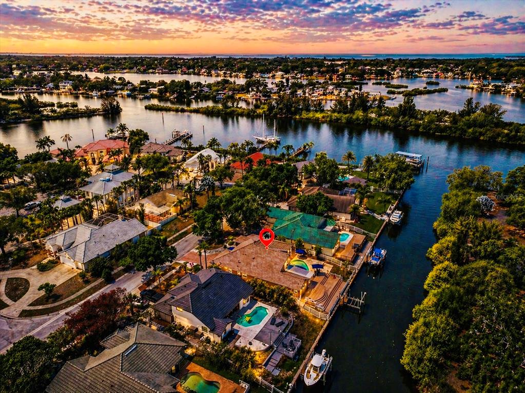 An aerial view of two waterfront houses with pools, wooden decks, and private boat docks — 1114 MARINA DRIVE, TARPON SPRINGS, FL