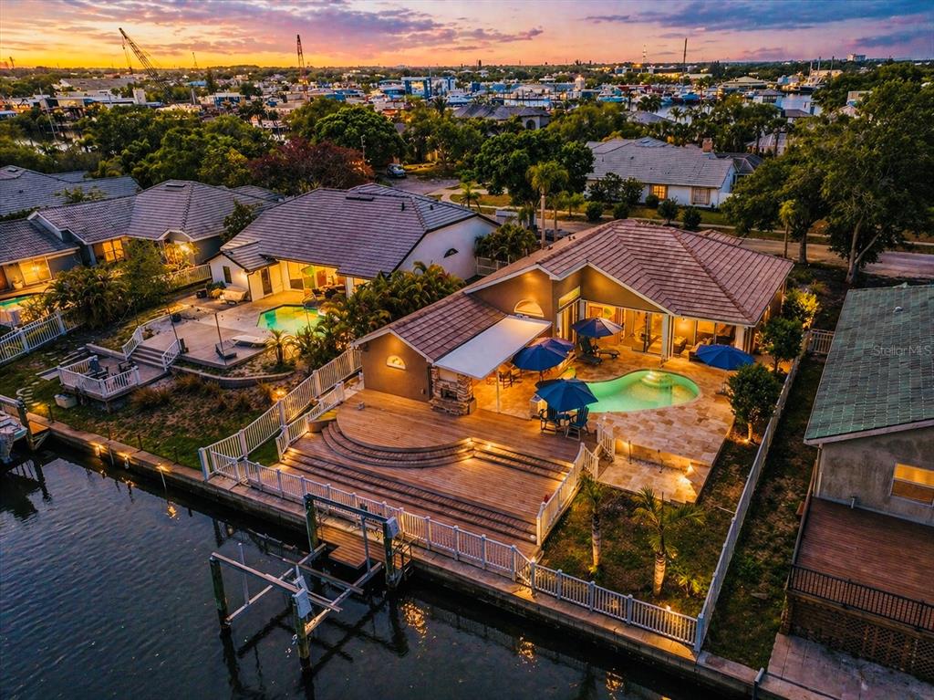 An aerial view shows a waterfront residential neighborhood with a canal, boat slips, and houses — 1114 MARINA DRIVE, TARPON SPRINGS, FL