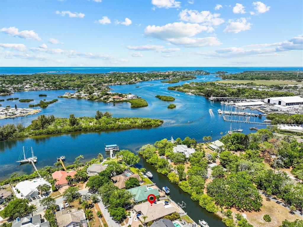 An aerial view shows a waterfront house with a red marker on a canal — 1114 MARINA DRIVE, TARPON SPRINGS, FL