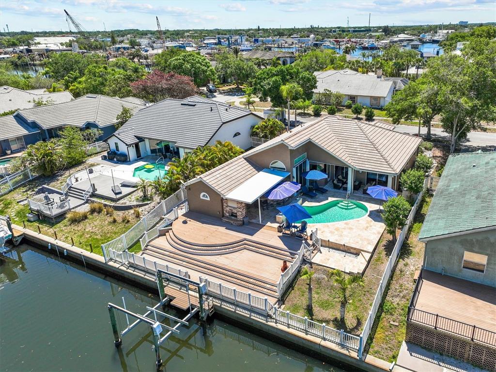 An aerial view shows a waterfront house with a multi-level deck, pool, and boat lift — 1114 MARINA DRIVE, TARPON SPRINGS, FL
