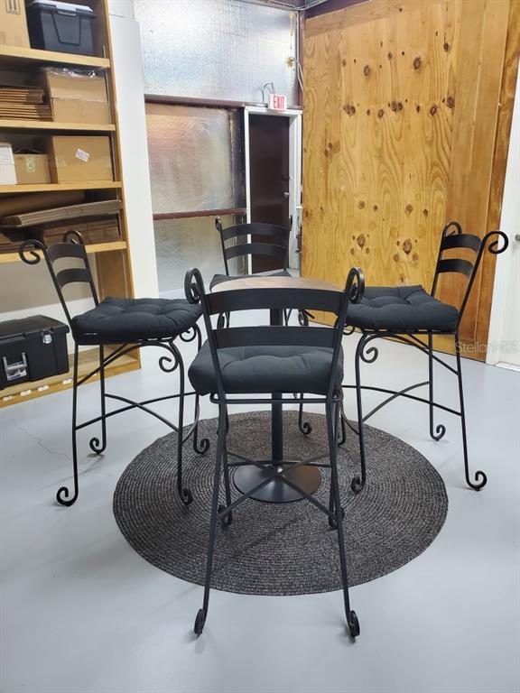 A small round table with four black metal bar stools sits on a circular rug — 2730 WORTH AVENUE UNIT 8, ENGLEWOOD, FL