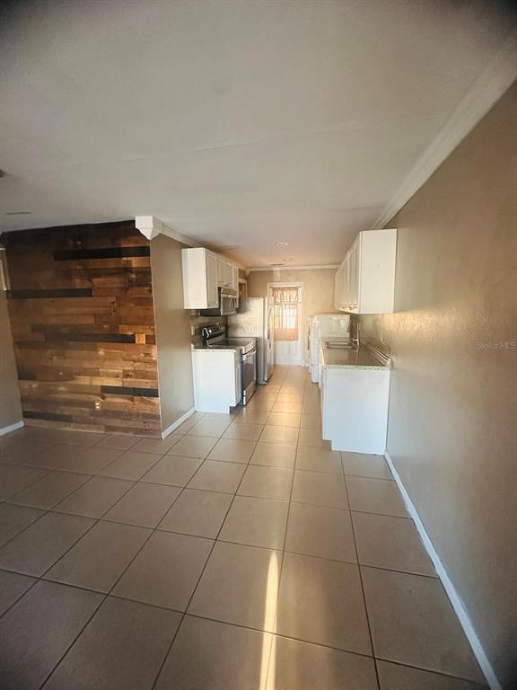 A kitchen features white cabinets, light countertops, and a wood-paneled accent wall — 502 WINTER TERRACE UNIT 121, WINTER HAVEN, FL