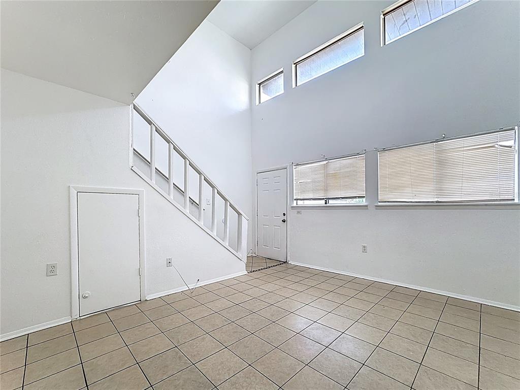 A room with tiled floors, a staircase, a small storage door, and high windows — 3944 CRAYRICH CIRCLE UNIT A-4, ORLANDO, FL