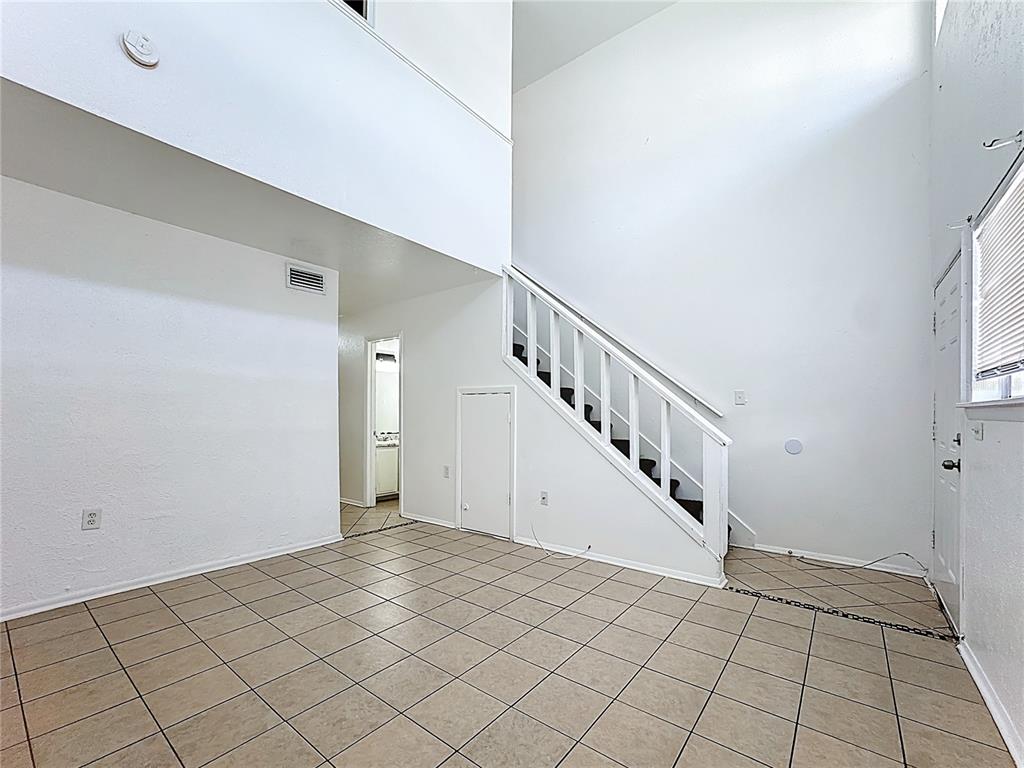 An interior view of a room with tiled floors, a staircase, and high ceilings — 3944 CRAYRICH CIRCLE UNIT A-4, ORLANDO, FL