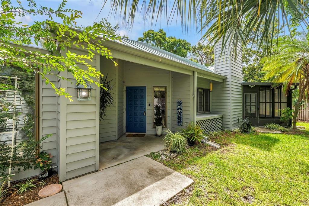 The exterior of a light green house features a blue front door and a screened porch — 10495 LONGWOOD DRIVE, SEMINOLE, FL