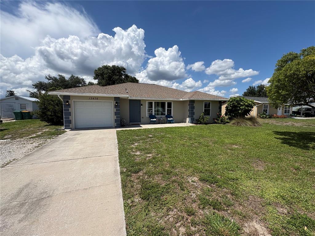 A single-story house with a beige exterior, a white garage door, and a concrete driveway — 13476 ROMFORD AVENUE, PORT CHARLOTTE, FL