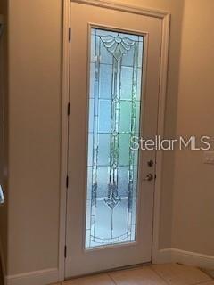 A white front door features a tall, decorative glass insert with a floral design — 213 LOURDAN COURT, DEBARY, FL