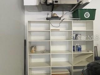 A white, multi-shelf storage unit stands against a wall in a garage-like space — 213 LOURDAN COURT, DEBARY, FL