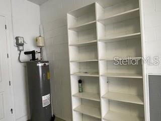 A utility room features a water heater next to a tall, white, multi-shelf storage unit — 213 LOURDAN COURT, DEBARY, FL