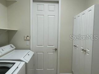 A laundry room features a white washer, a closed door, and white storage cabinets — 213 LOURDAN COURT, DEBARY, FL