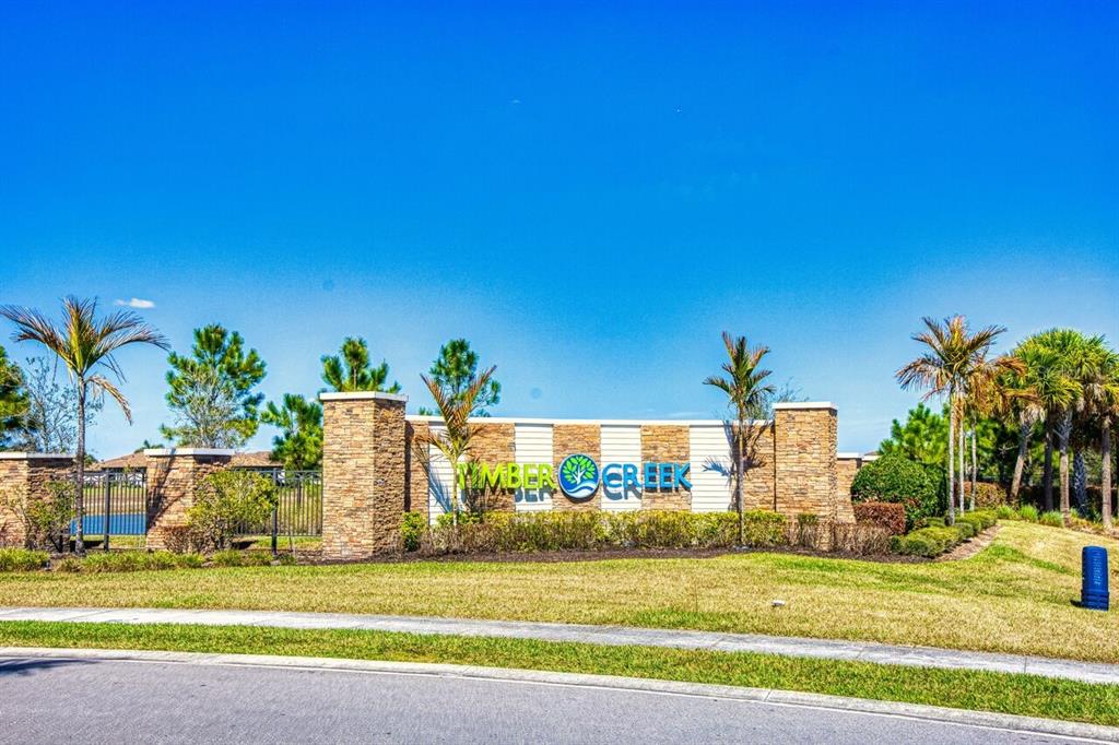 A stone and white monument sign for Amber Creek stands in a landscaped residential area — 10903 TIMBER CREEK DRIVE, FORT MYERS, FL