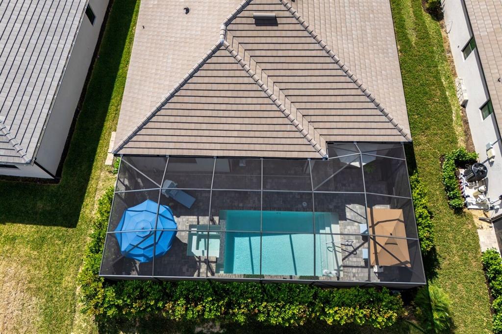 An aerial view shows a house with a tiled roof and a screened-in pool patio — 10903 TIMBER CREEK DRIVE, FORT MYERS, FL