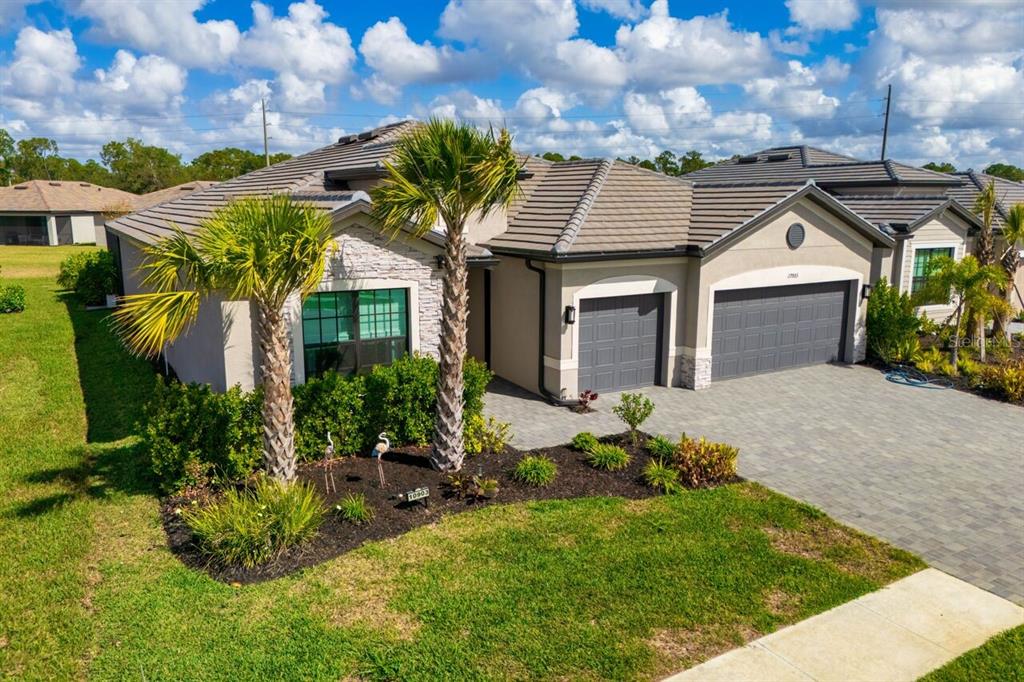 An exterior view of a single-story house with a tiled roof, stone accents, and two garages — 10903 TIMBER CREEK DRIVE, FORT MYERS, FL