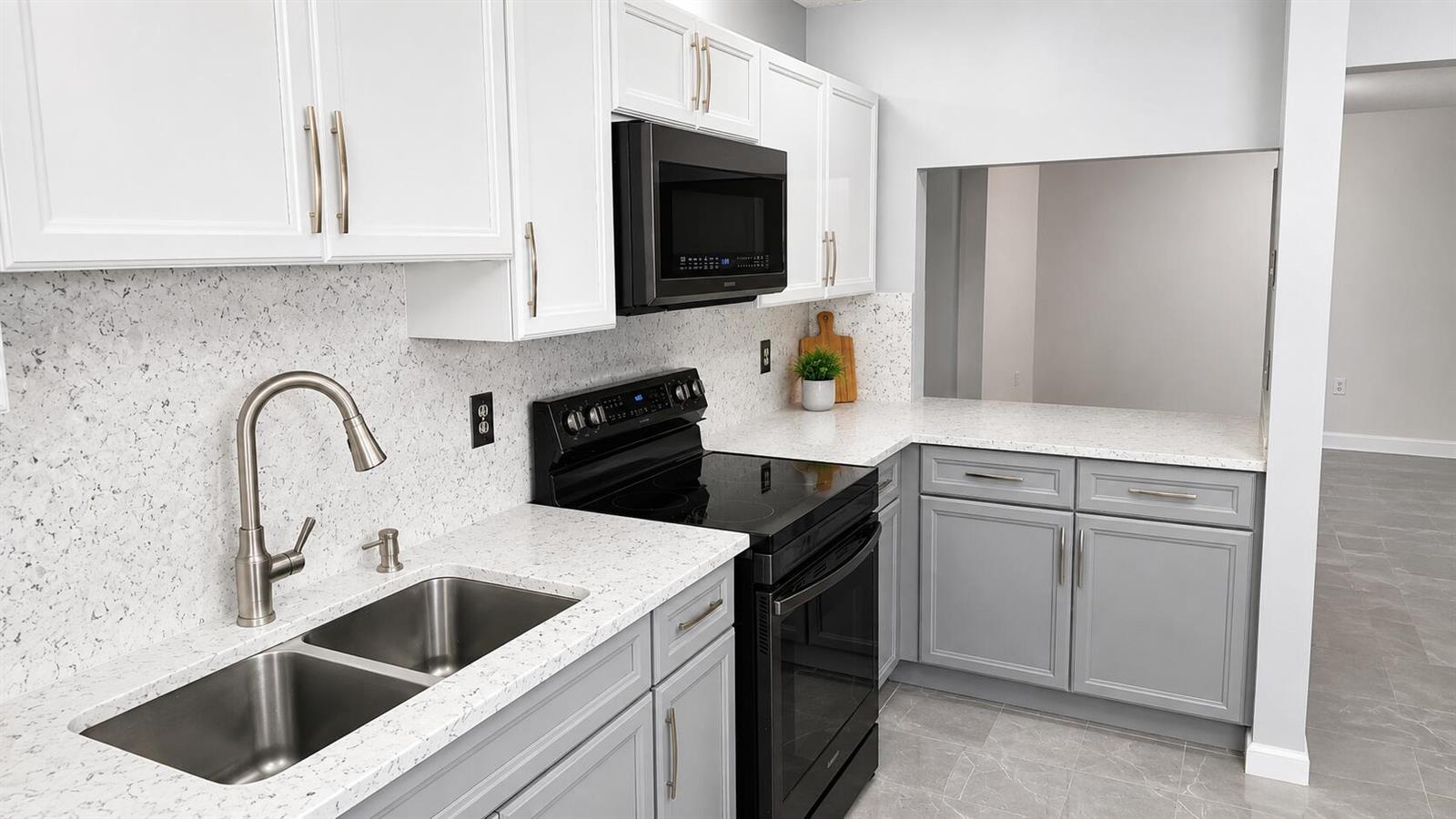 A kitchen features white upper cabinets, gray lower cabinets, black appliances, and speckled quartz countertops — 9364 Sable Ridge Circle # B, Boca Raton FL 33428, BOCA RATON, FL