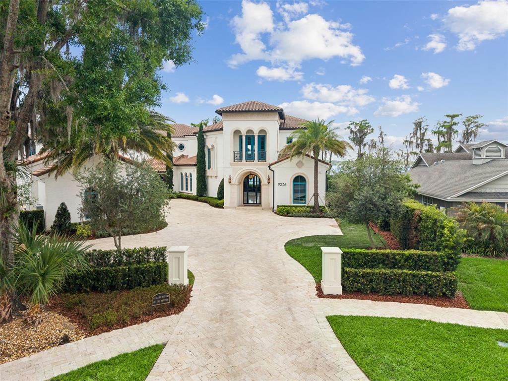 A large Mediterranean-style house features a stone driveway, arched entryway, and a tiled roof — 9236 BAY POINT DRIVE, ORLANDO, FL